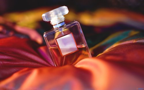 Pink perfume bottle laying in soft, luxurious sheets