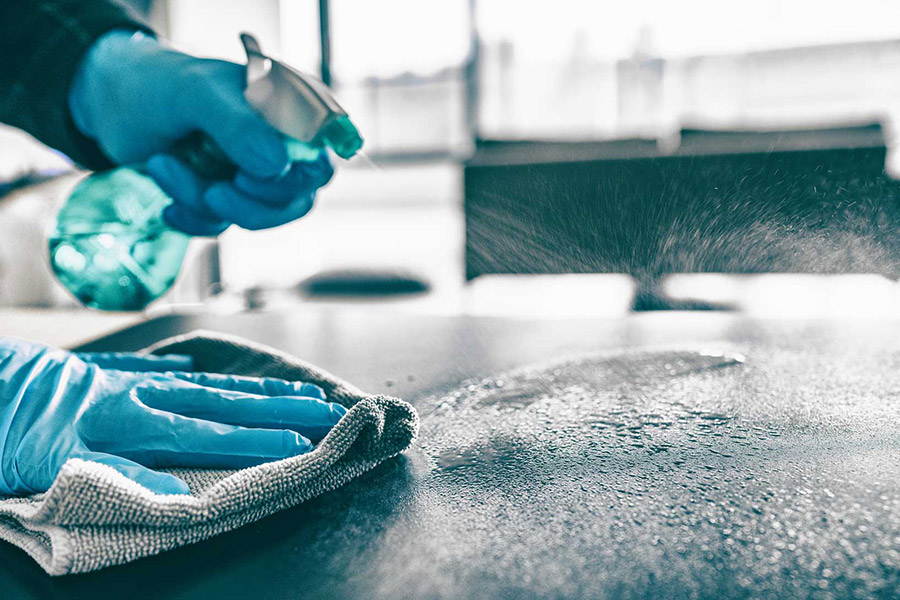 supplyone blog case study cleaner wearing gloves spraying and wiping surface